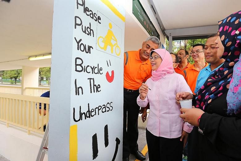 Marsiling-Yew Tee GRC MP Halimah Yacob, fresh from adding a painted smiley face to the underpass entrance at an event yesterday marking the RC's adoption of the public walkway. The RC will engage cyclists to promote habits such as dismounting before 