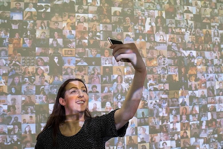 A gallery assistant in front of an audio-visual installation, titled Hello World! (2008), by American artist Christopher Baker at a press preview for the exhibition From Selfie To Self-Expression at London's Saatchi Gallery.