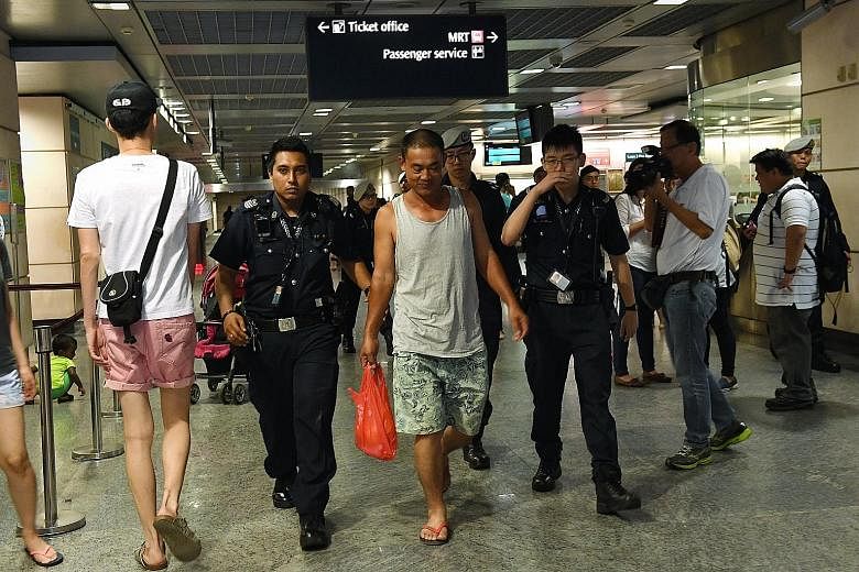 Police escorting the man who deliberately left his bag at the platform of Hougang MRT Station yesterday while he ran an errand.