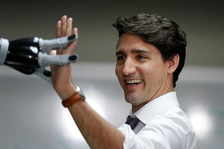 Canadian Prime Minister Justin Trudeau high-fiving a robotic hand at a firm in Quebec. He may have a more delicate task on his hand, juggling ties with China.