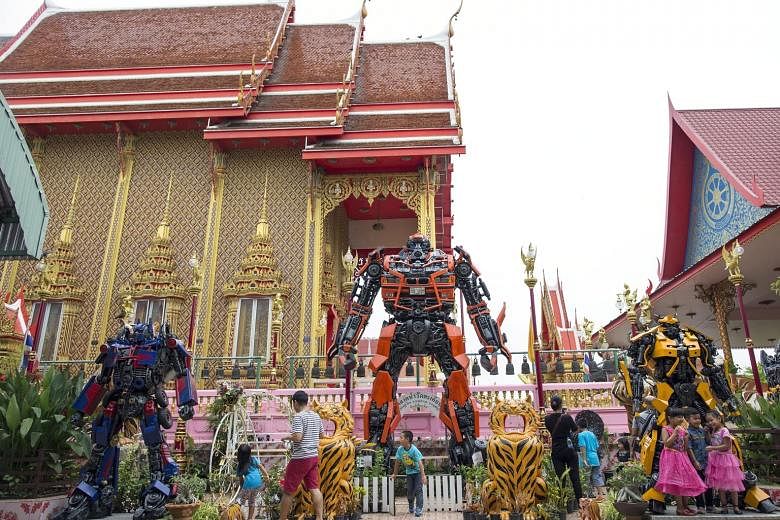 Thai children having fun with Transformer statues at Wat Takien temple in Nonthaburi province, Thailand, last Saturday. A Buddhist abbot decorated the temple with the statues, made from scrap metal, to inspire and attract children, young people and t