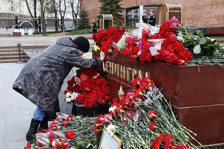 Flowers were laid in memory of the victims of the St Petersburg metro blast at a memorial stone reading "Leningrad" near the Kremlin wall in Moscow yesterday. Media reports said at least 14 people were killed and dozens hurt in the blast on Monday. R