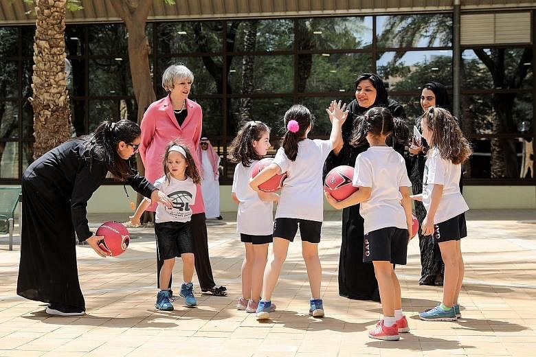 British Prime Minister Theresa May with Saudi Princess Reema bint Bandar Al Saud (seen here high-fiving a pupil) during a visit to the General Sports Authority's Leadership Institute in Riyadh, Saudi Arabia, yesterday.