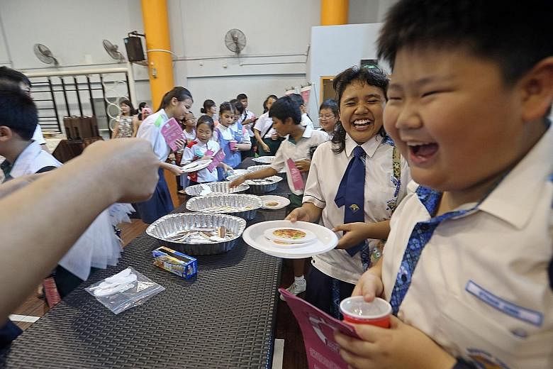 Ethan Ang and Siti Syazwana of South View Primary School, both 11, participating in a game at a station on the educational trail yesterday. The simulated buffet highlights the importance of not wasting food.