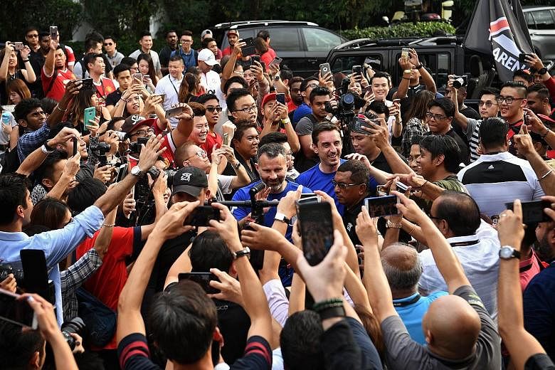 Former Manchester United stars Ryan Giggs (left) and Gary Neville surrounded by fans at Woodleigh Park yesterday. Giggs said the Red Devils need midfielders or even defenders to chip in with goals, while Neville said Jose Mourinho's men have failed t