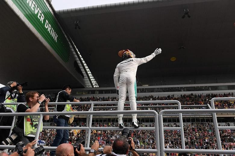 A delighted Lewis Hamilton waving to fans from the pit wall after beating Vettel by 0.186sec. It was the British driver's fourth pole in China in five years.