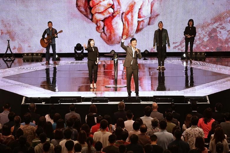 City Harvest Church pastor Kong Hee on stage with his wife Ho Yeow Sun at the church's weekend service yesterday, a day after the six church leaders had their sentences generally halved on appeal.