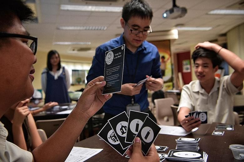 Bukit Batok Secondary School students Calvin Lim (with spectacles) and Edgar Pang, both 16, play a card game based on the book The Joy Luck Club under the tutelage of their teacher Ow Yeong Wai Kit.