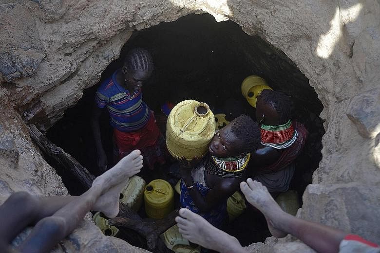 A young girl on March 21 passing a jerrycan filled with murky water trickling from underground rocks to others waiting above the watering hole in Turkana county in Kenya, where a biting drought has ravaged the livestock population and the nation's fo