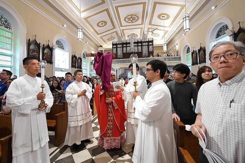 Left: Catholic Archbishop William Goh leading the congregation in the Veneration of the Cross during a Good Friday service at the Cathedral of the Good Shepherd yesterday. It was the first Good Friday service commemorated by the church in Queen Stree