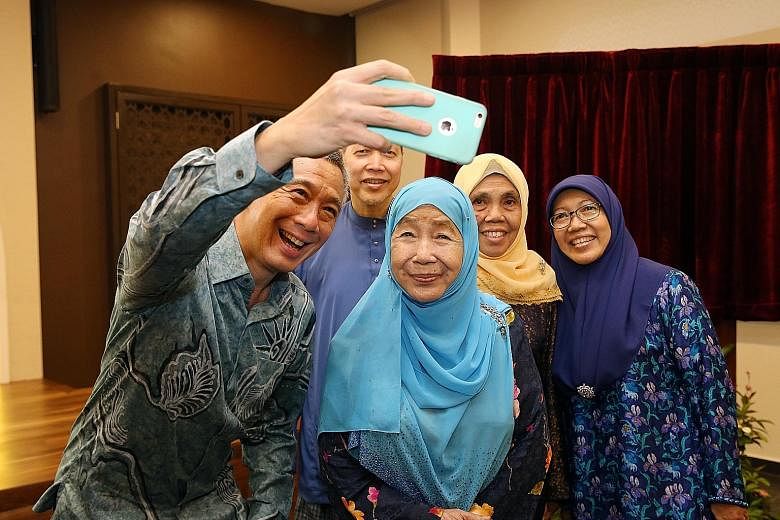 Prime Minister Lee Hsien Loong taking a wefie with Puan Noor Aishah, widow of President Yusof Ishak, and the Yusofs' children (from left) Imran Yusof, Orchid Kamariah and Zuriana Yusof at the Yusof Ishak Mosque yesterday. Above: Worshippers at the pr