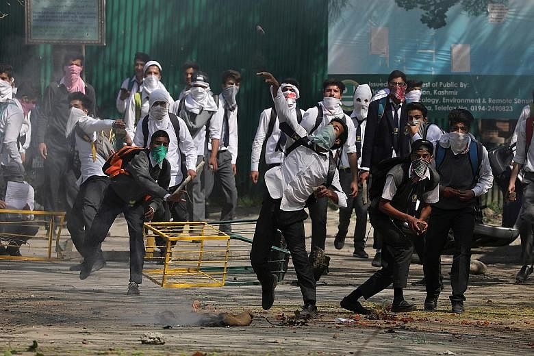 Students hurling stones at police in Srinagar yesterday to protest against students being injured in clashes with security forces.