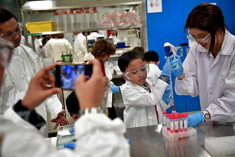 Adyan Ul-Haque, 10, using a red dye to test for acids and bases while on a tour of biotechnology firm Shire's manufacturing plant in Woodlands to mark World Haemophilia Day yesterday. He and his mother were among 11 visitors picked by the Haemophilia
