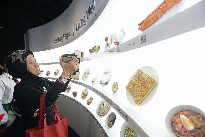 Junyuan Primary vice-principal Hafsah Abdullah checking out her choice of food in an interactive exhibit at the revamped Kidney Discovery Centre of the National Kidney Foundation yesterday. The exhibit allows visitors to calculate the calories and su