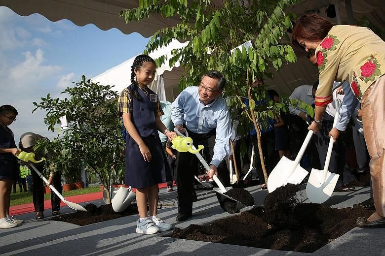 Health Minister Gan Kim Yong planting a tree with an Admiralty Primary School pupil and Alexandra Health System chairman Jennie Chua at the Woodlands Health Campus' ground-breaking ceremony yesterday.