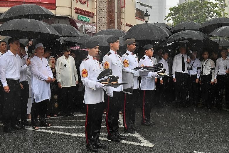 Mourners, including Mr Lee Hsien Loong, watching as Mr Othman Wok's coffin was loaded onto the gun carriage at Sultan Mosque yesterday.