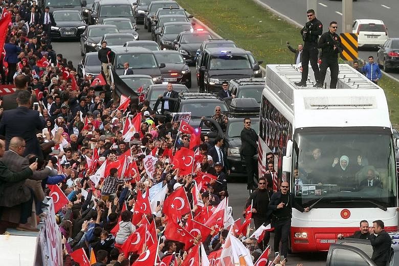 Turkish President Recep Tayyip Erdogan and his wife Emine acknowledging supporters from a bus during a parade in Ankara on Monday, following the referendum result which granted the head of state extra powers.