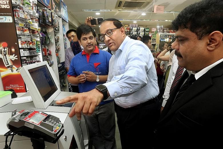 General manager S. Janakiraman (in blue) of Food-Joy, among the first micro-retailers here to adopt self-checkout machines, with Minister S. Iswaran (centre) during a learning journey for such retailers yesterday.