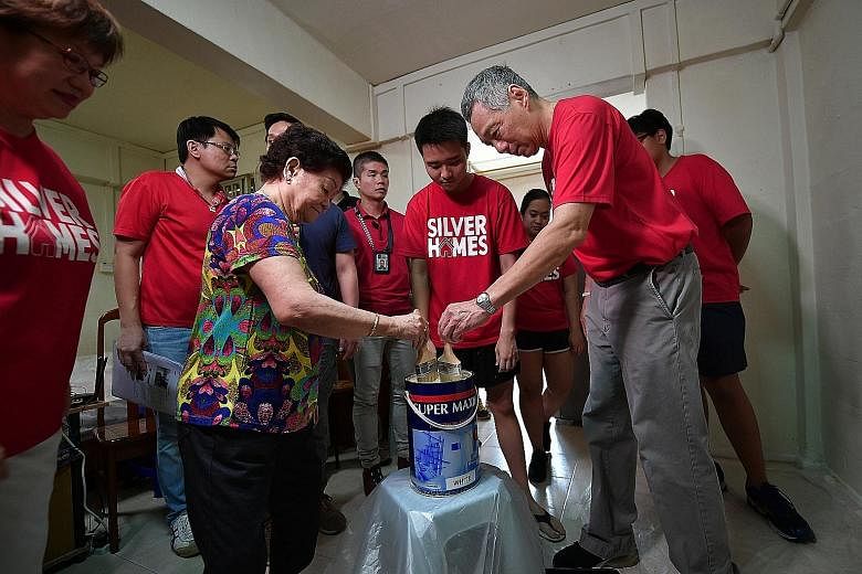 Prime Minister Lee Hsien Loong helping Madam Chen Yueh Lun paint her one-room rental flat together with student volunteers. With them is Central Singapore District Mayor Denise Phua (far left).