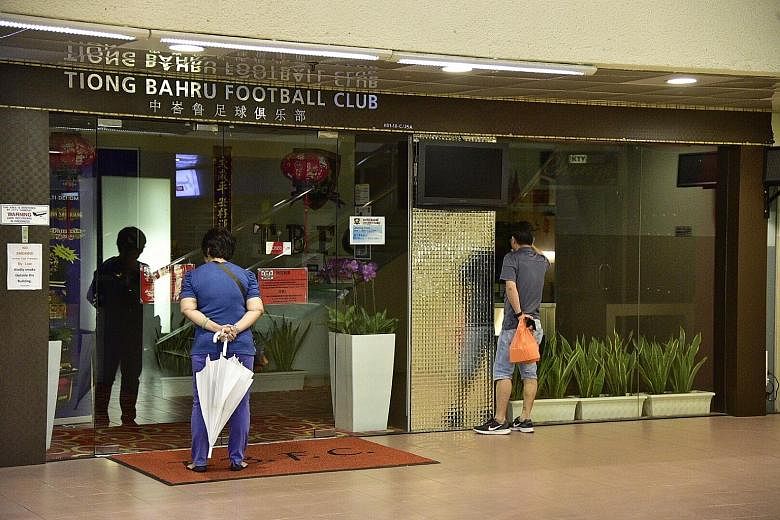 A man and a woman looking in on the Tiong Bahru FC clubhouse at People's Park Centre yesterday. It has been closed since Thursday's CAD raid.