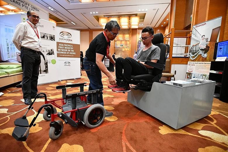 Managing director of Radiance Medical Systems Steven Ho, 51, demonstrating how to retract the wheel so that a user can move smoothly out of a transfer wheelchair into a chair, watched by managing director of Winner SG Michael Pang, 66. The world's fi