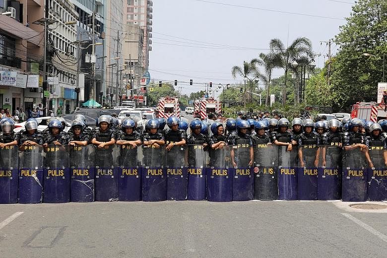 Anti-riot police officers blocking protesters yesterday in Manila, which is hosting Asean meetings. Ahead of the summit today, regional leaders have instructed officials to try to conclude a regionwide trade pact by the end of this year. Also on the 