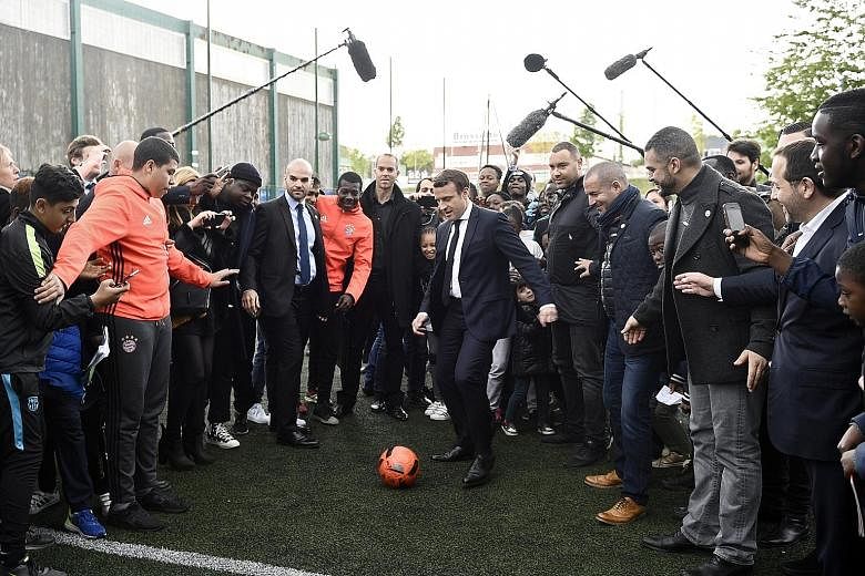 French presidential candidate Emmanuel Macron kicking a football during a campaign visit to Sarcelles, north Paris, on Thursday. The camp has accused Russia of attacking its databases, fuelling suspicions that the Kremlin is trying to undermine the c