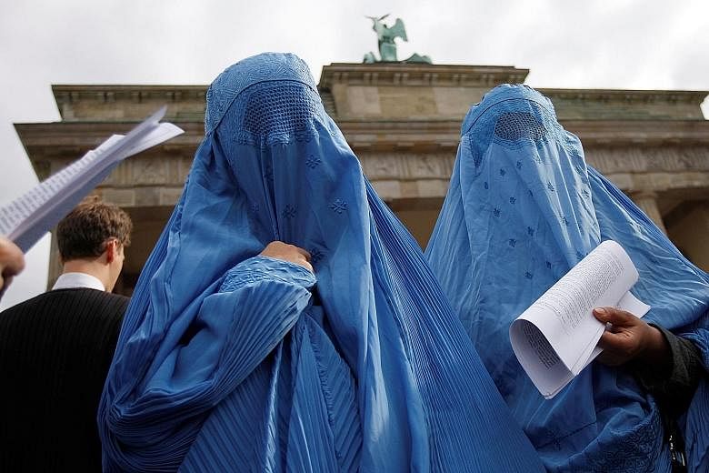 Burqa-clad protesters in front of the Brandenburg Gate in Berlin. German lawmakers yesterday passed new security measures, including a partial ban on the full-face Islamic veil.