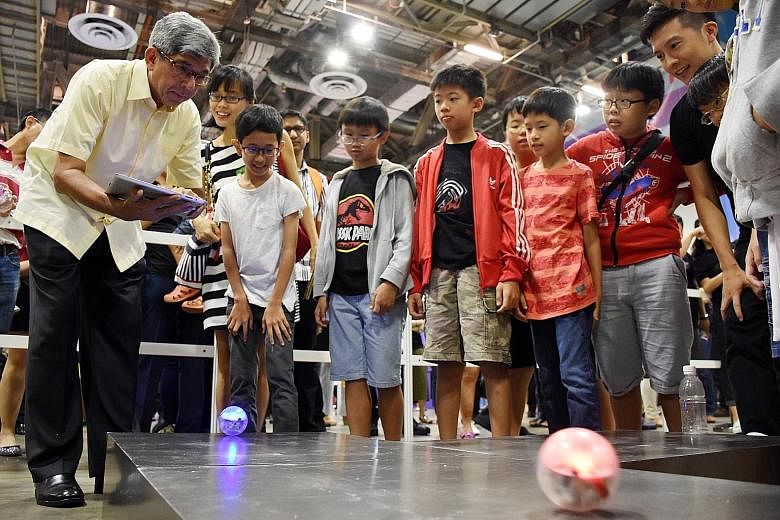 Dr Yaacob Ibrahim taking part in a game that involves navigating electronic balls with a tablet at Tech Saturday (Upsized!) yesterday. The two-day carnival focuses on products and services helping Singapore's digital economy transformation.