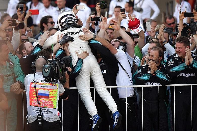 Valtteri Bottas celebrating his first F1 win at the Russian Grand Prix with the Mercedes crew. Ferrari's Sebastian Vettel and Kimi Raikkonen finished second and third respectively, with drivers' championship leader Vettel (86 points) extending his ad