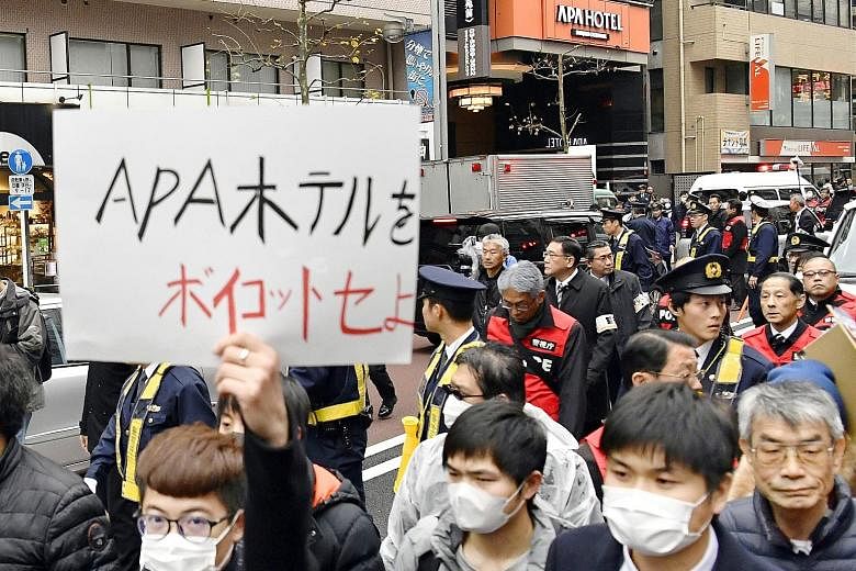 Chinese residents in Tokyo marching at a protest against the Japanese hotel chain APA Group in February. The owner of the chain came under fire for hate speech earlier this year. A sign reading "Prime Minister Shinzo Abe" hanging from a masakaki tree