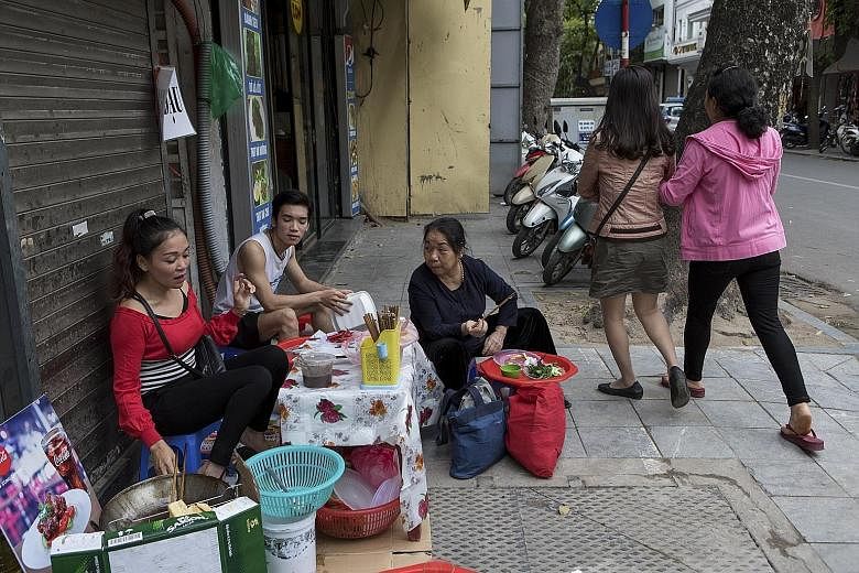 A street vendor in Hanoi, Vietnam. Sidewalk stalls still appeal to people of nearly all social classes in South-east Asia.