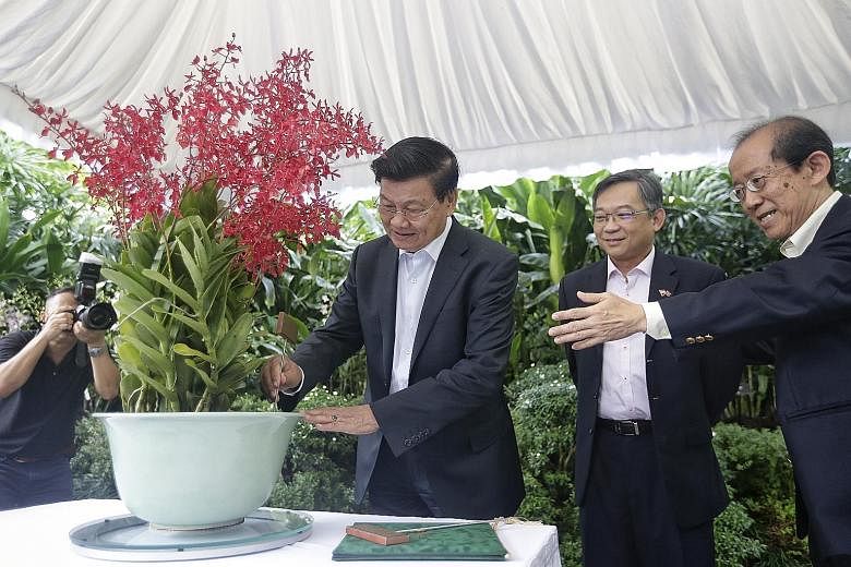 Above: Laos Prime Minister Thongloun Sisoulith at an orchid naming ceremony at the National Orchid Garden yesterday, where the Renanthera Thongloun Sisoulith was named after him. With him are Health Minister Gan Kim Yong (centre) and National Parks B