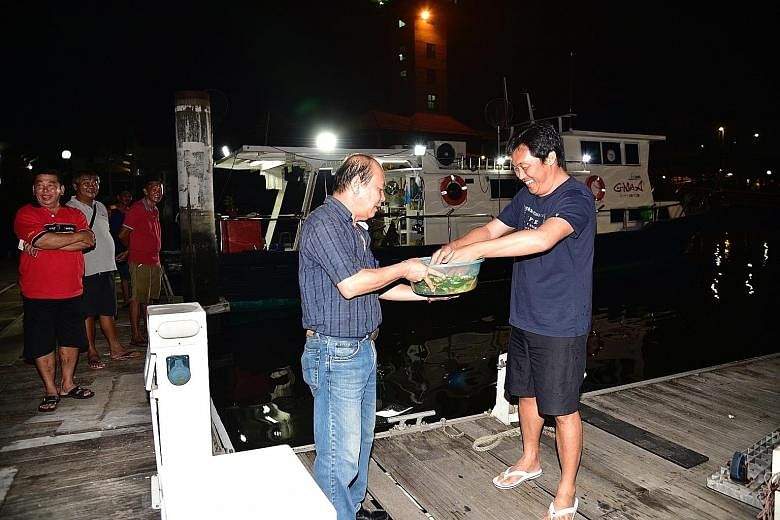 Boat captain Ricky Tan (right) performing a ritual to wash away bad luck with the help of his friend Paulson Yuen after arriving at Marina Country Club early this morning.