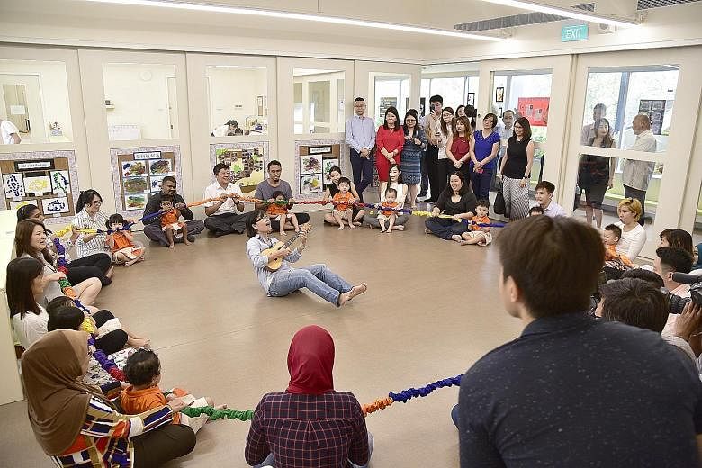Minister for Education (Schools) Ng Chee Meng with pre-schoolers and their parents and teachers at a music and movement session, as Ms Lavina Chong (in front of the minister, with ukulele), a training artist selected by NAC, leads them in a song.