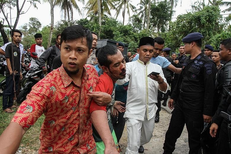 A prisoner being taken back by a plainclothes officer after escaping yesterday from the Sialang Bungkuk jail in Pekanbaru, Riau province, Sumatra. The inmates escaped when guards allowed them to join Friday prayers.