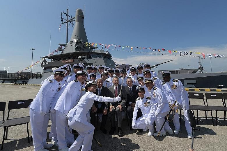 Prime Minister Lee Hsien Loong, flanked by Deputy Prime Minister Teo Chee Hean and Defence Minister Ng Eng Hen, sitting for a wefie with the crew of littoral mission vessel RSS Independence, which can be seen in the background.