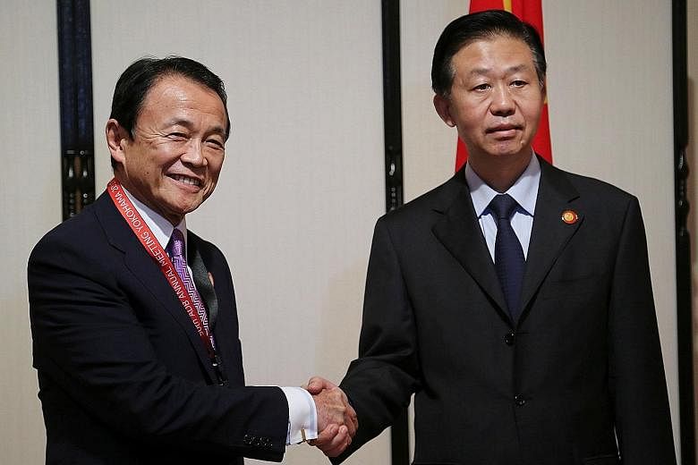 Japanese Finance Minister Taro Aso (left) and his Chinese counterpart Xiao Jie in Yokohama, Japan, yesterday. They did not discuss issues such as geopolitical risks from North Korea's nuclear programme during the dialogue.