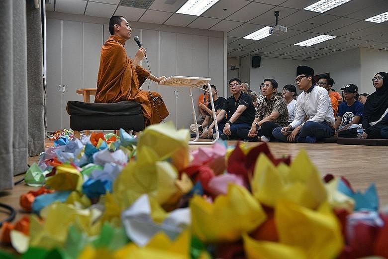 Venerable Phra Chun Kiang speaking at the Buddhist Fellowship East Centre yesterday, surrounded by paper lotus flowers that stand for purity in the Buddhist faith. Listening is South East District Mayor Maliki Osman (first row, second from right), wh