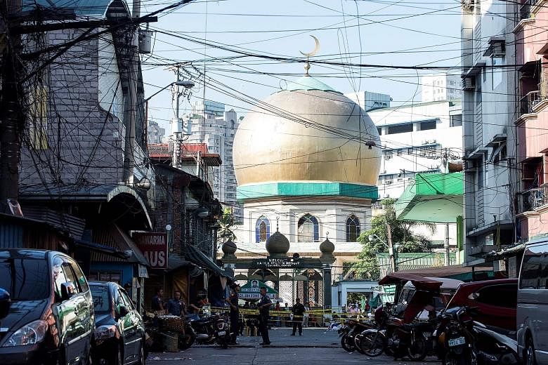 Police officers standing guard outside a mosque in Quiapo, Manila, on Saturday, after two explosions rocked the office of Shi'ite cleric Nasser Abinal in the same area.