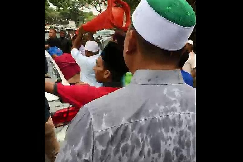 Some members of the mosque congregation attacking the white car with plastic cones and a helmet after the driver honked repeatedly during Friday prayers in a Johor housing estate when his way was blocked.
