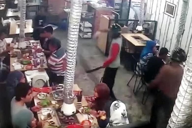 A screen grab from a video posted on social media showing machete-wielding men, wearing full-faced motorcycle helmets, raiding a restaurant in Taman Melawati, Ampang, last Saturday night. They escaped with about RM30,000 (S$9,700) in cash and valuabl