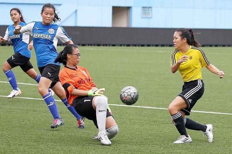 VJC's Tiffany Low attempting a shot at goal against MJC goalkeeper Christine Lim as defenders Nuryn Aqidah (front) and Nadiah Amalina look on. VJC won the A Division final 3-2 on penalties after a 1-1 draw at the Jalan Besar Stadium yesterday.