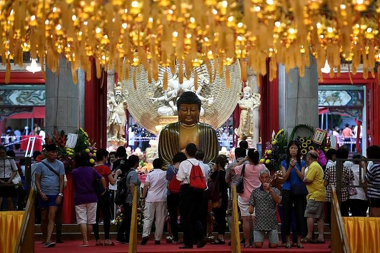 Devotees at Kong Meng San Phor Kark See Monastery in Bright Hill Road yesterday. The monastery is marking this year's Vesak Day for a month with the theme of "Season of Gratitude". Above: Devotees (from left) Macsonn Anjaya, four, Madam Audrey Ang, 6
