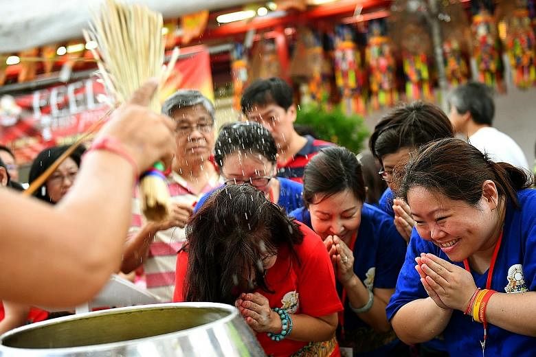 Thekchen Choling Tibetan Buddhist temple devotees at the Sangha blessing corner. The sprinkling of water blessings is meant to symbolise purification.