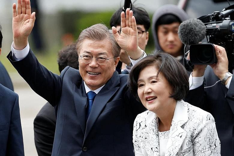 Mr Moon Jae In and his wife Kim Jung Sook greeting supporters as they arrived at the presidential Blue House in Seoul yesterday. To stay close to the people, the newly sworn-in president plans to move the presidential office from the heavily guarded 