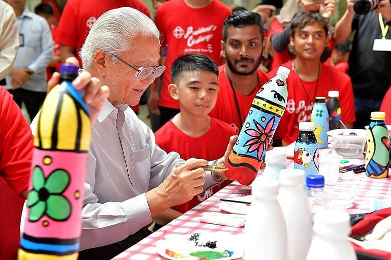 Meridian Secondary School student Adry Fariqaeen, 12, observing President Tony Tan Keng Yam at a bottle art and bag painting workshop at the People's Association (PA) headquarters in King George's Avenue yesterday. At the event, PA chief executive di