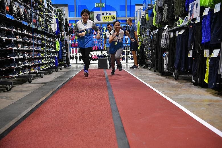 Decathlon staff members putting their track shoes to use at the in-store running track in its latest Joo Koon outlet yesterday. The track is one of the "experience zones" available for the use of its patrons at the 4,000 sq m outlet, the biggest of t
