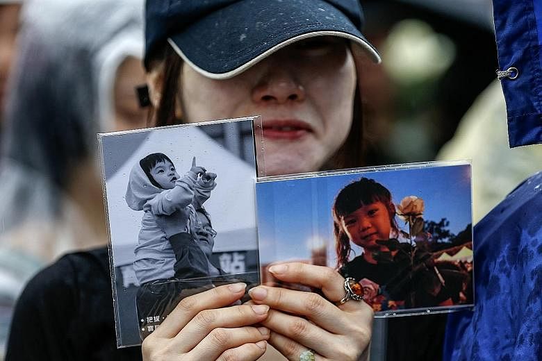 A protester holding photos of the four-year-old victim in April last year. Wang Ching-yu killed her on a Taipei street in front of her mother.