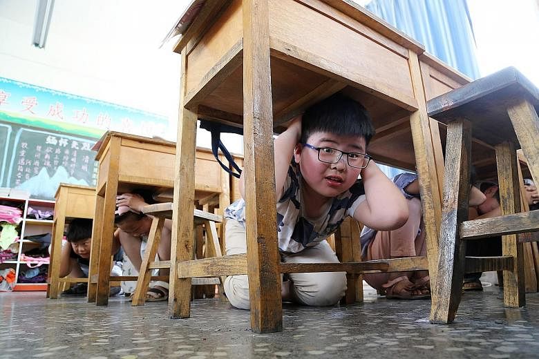 Children crouching under the tables in a classroom during a safety drill at The Third Experimental Primary School in Wen County in China's central Henan province yesterday, on the ninth anniversary of the 2008 Sichuan earthquake. The 8.0-magnitude qu